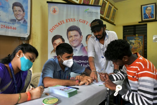 Le personnel de l'hôpital ophtalmologique Narayana Nethralaya aide un volontaire à remplir un formulaire de don des yeux lors d'un événement à la mémoire de l'acteur Puneeth Rajkumar à Bangalore le 18 novembre 2021
