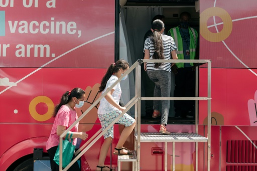 Unee famille vient se faire vacciner contre le Covid-19 dans un bus transformé en centre de vaccination itinérant, le 5 juin 2021, dans le quartier du Queens à New York
